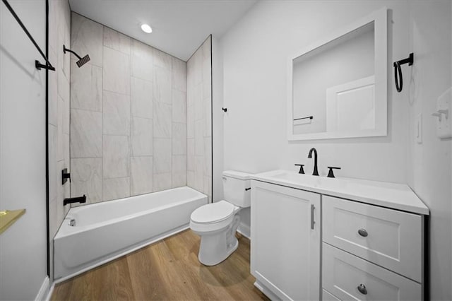 bathroom with vanity, washtub / shower combination, wood finished floors, baseboards, and toilet