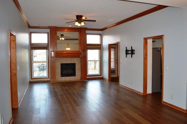 unfurnished living room with crown molding, a tile fireplace, dark hardwood / wood-style floors, and ceiling fan