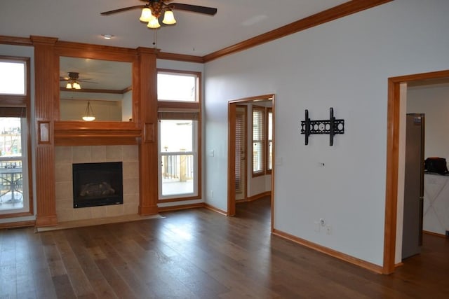 unfurnished living room with dark wood-type flooring, ceiling fan, ornamental molding, and a tiled fireplace