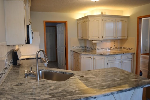 kitchen with white cabinetry, sink, and tasteful backsplash