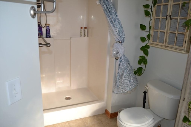 bathroom featuring tile patterned flooring, toilet, and a shower