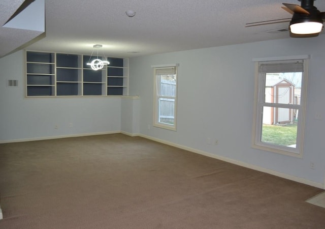 carpeted spare room featuring ceiling fan, a textured ceiling, and a healthy amount of sunlight