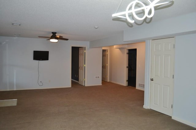 unfurnished room with a textured ceiling, ceiling fan, and carpet flooring