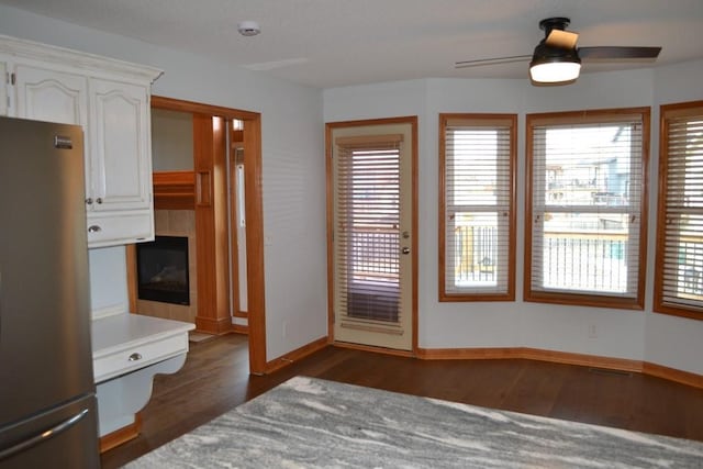 interior space with a tiled fireplace, a wealth of natural light, dark hardwood / wood-style floors, and ceiling fan