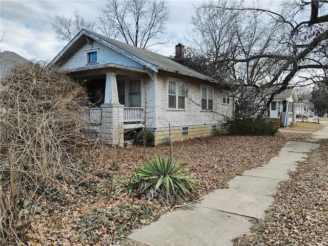 view of home's exterior featuring a porch, crawl space, and a chimney