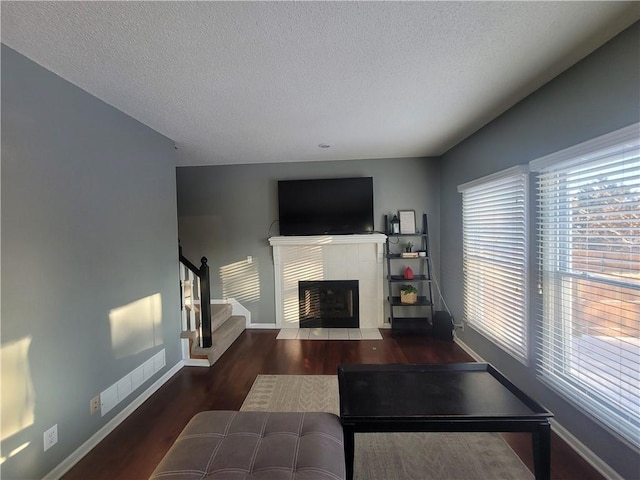 living room featuring dark hardwood / wood-style flooring, a tiled fireplace, and a textured ceiling