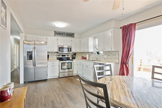 kitchen featuring dark hardwood / wood-style flooring, decorative backsplash, white cabinets, and appliances with stainless steel finishes