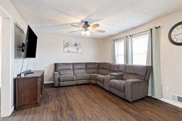 living room featuring dark wood-type flooring, ceiling fan, and a textured ceiling