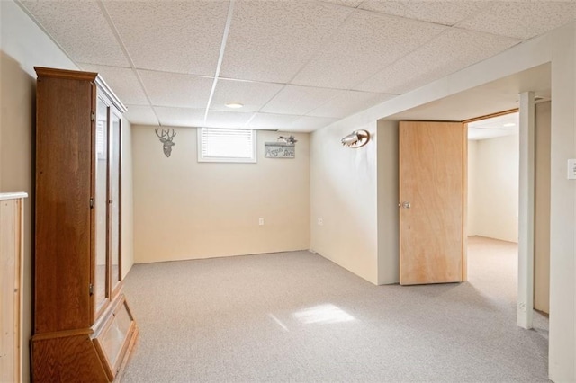 basement featuring a paneled ceiling and light carpet