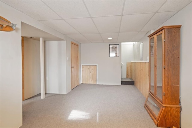 interior space with a drop ceiling and light colored carpet