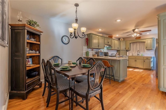 dining room featuring sink, ceiling fan with notable chandelier, and light hardwood / wood-style floors