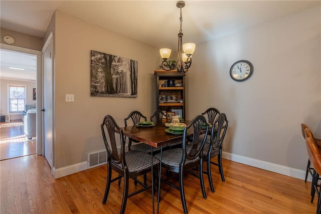 dining space with an inviting chandelier and light hardwood / wood-style flooring