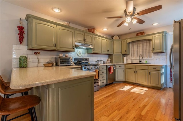 kitchen with appliances with stainless steel finishes, sink, decorative backsplash, light hardwood / wood-style floors, and kitchen peninsula