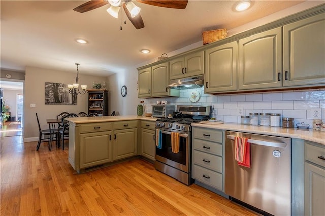 kitchen with decorative light fixtures, decorative backsplash, kitchen peninsula, stainless steel appliances, and light hardwood / wood-style flooring