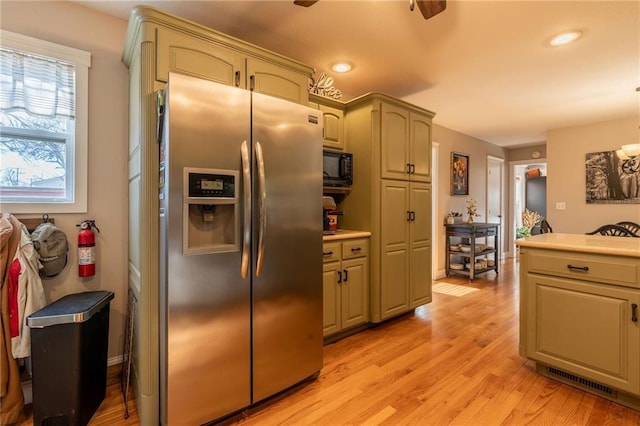 kitchen with black microwave, stainless steel refrigerator with ice dispenser, ceiling fan, and light hardwood / wood-style floors