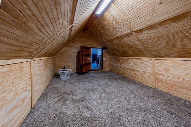 additional living space with vaulted ceiling, wooden ceiling, wood walls, and carpet