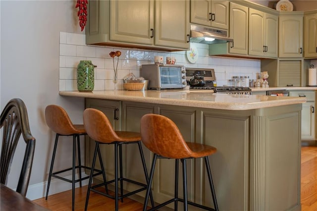 kitchen with stove, tasteful backsplash, a breakfast bar, and kitchen peninsula