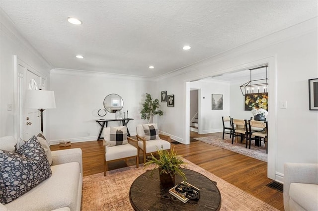 living room featuring crown molding, stairway, wood finished floors, and a textured ceiling