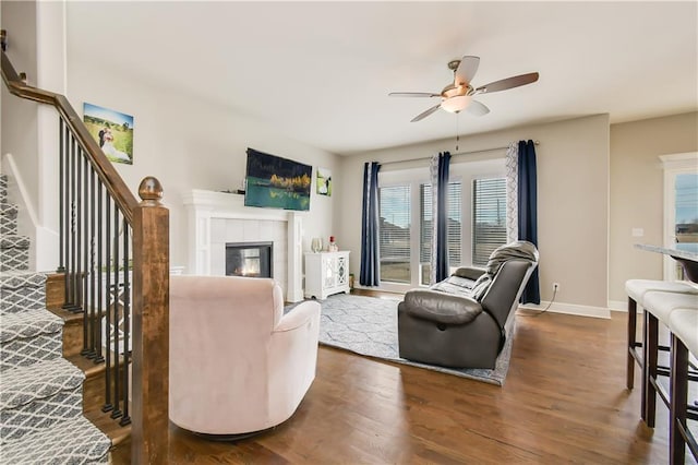 living room featuring ceiling fan, dark hardwood / wood-style floors, and a fireplace