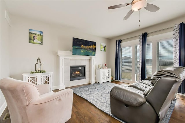 living room featuring dark wood-type flooring, ceiling fan, and a fireplace