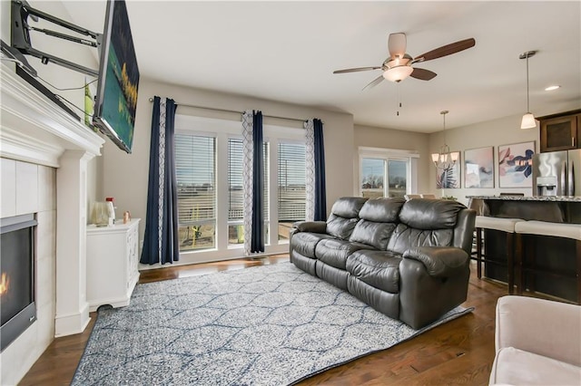 living room with a fireplace, dark hardwood / wood-style flooring, and ceiling fan with notable chandelier