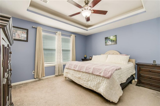 bedroom featuring light carpet, ceiling fan, and a tray ceiling