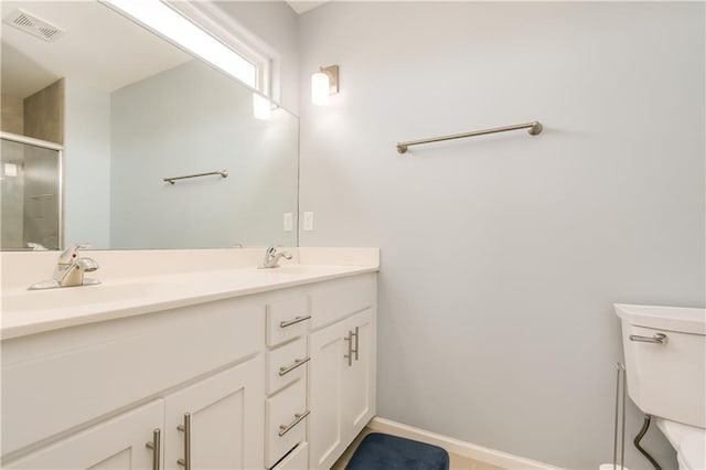 bathroom featuring vanity, a shower with shower door, and toilet