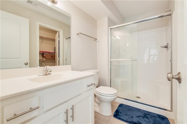 bathroom featuring tile patterned flooring, vanity, toilet, and a shower with shower door