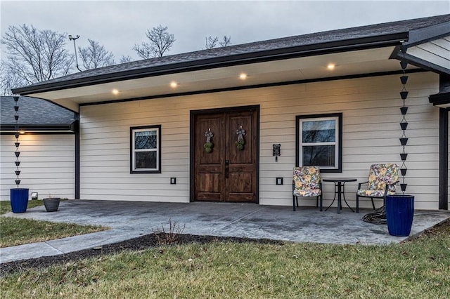 entrance to property featuring a patio area and a lawn