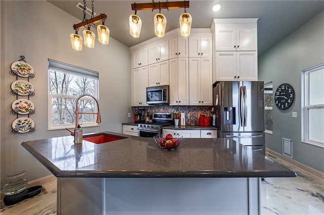 kitchen featuring white cabinetry, sink, dark stone counters, hanging light fixtures, and stainless steel appliances