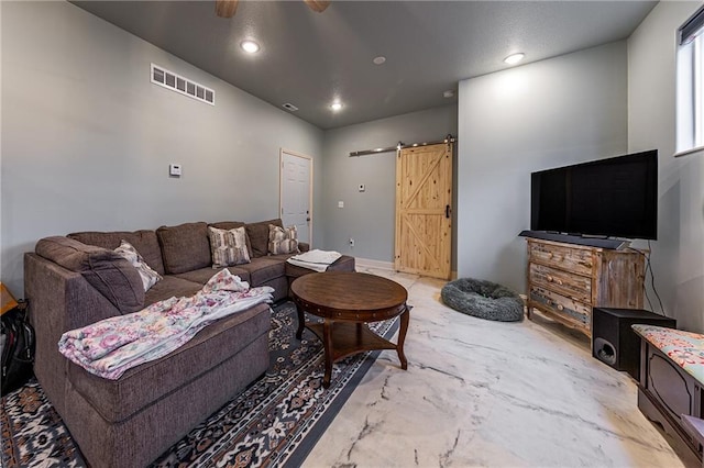 living room with a barn door and ceiling fan