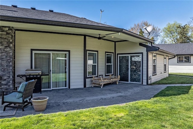 back of property featuring a lawn, a shingled roof, and a patio