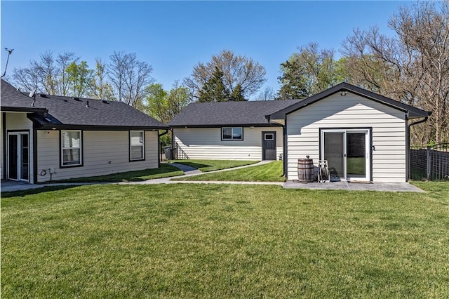 back of house with fence, a yard, a patio, and a shingled roof