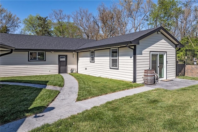single story home with fence, a shingled roof, and a front lawn