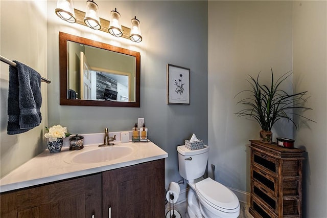 bathroom featuring toilet, vanity, and baseboards