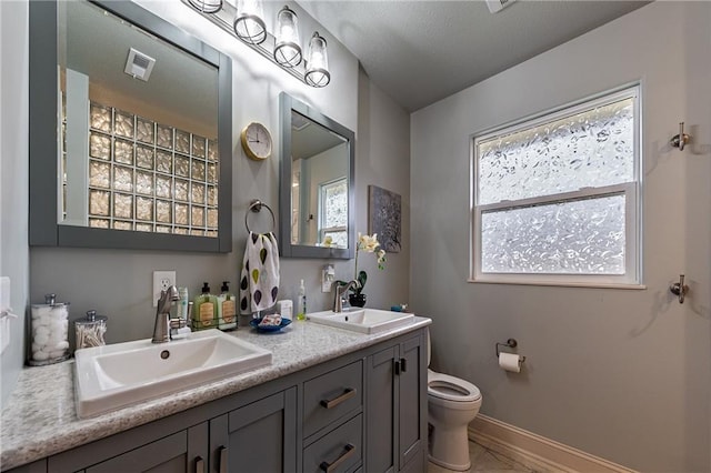 bathroom featuring visible vents, toilet, a healthy amount of sunlight, and a sink
