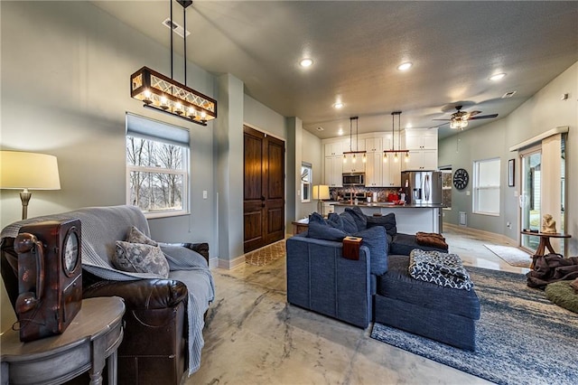 living room with a ceiling fan, baseboards, recessed lighting, and concrete flooring