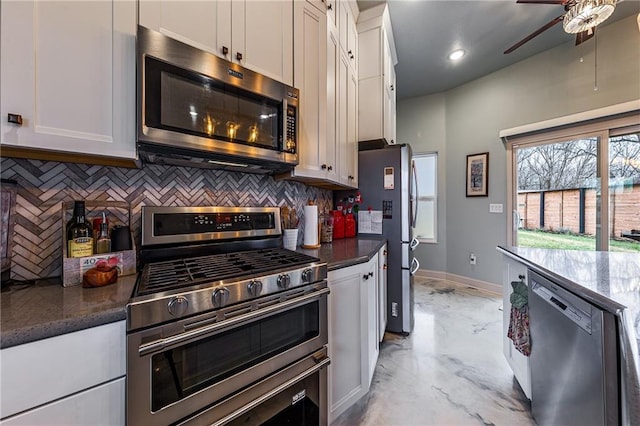 kitchen with white cabinets, stainless steel appliances, baseboards, backsplash, and ceiling fan