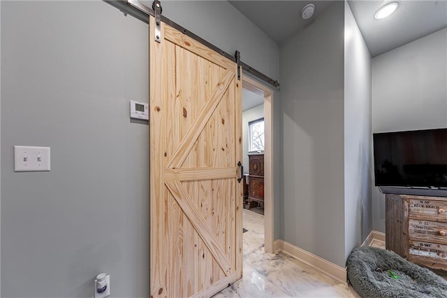 interior space with baseboards, marble finish floor, and a barn door