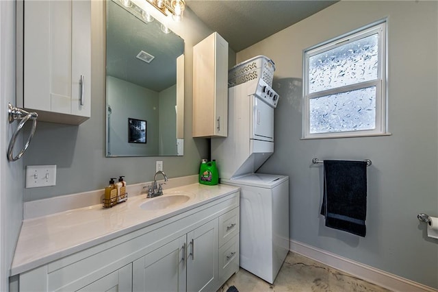 bathroom featuring baseboards, stacked washing maching and dryer, visible vents, and vanity