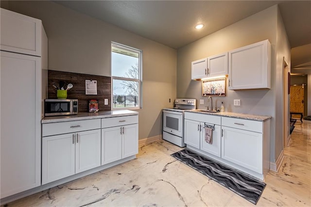 kitchen featuring white range with electric stovetop, a sink, stainless steel microwave, baseboards, and white cabinetry
