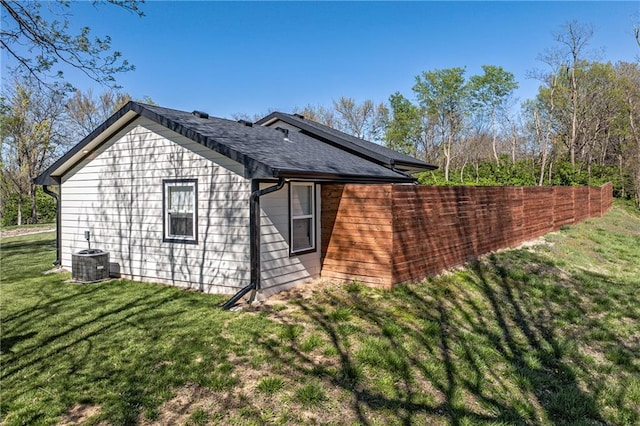 view of side of home with central AC and a yard