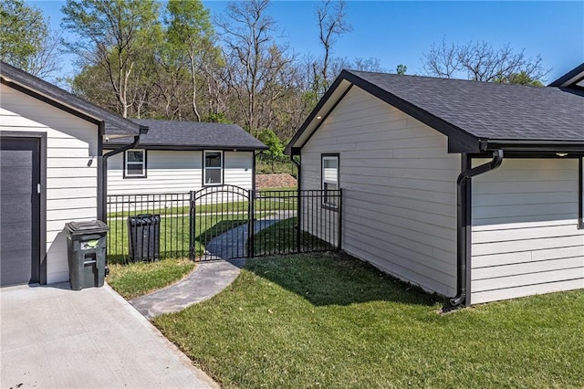 view of side of property with a lawn, a gate, fence, and a shingled roof