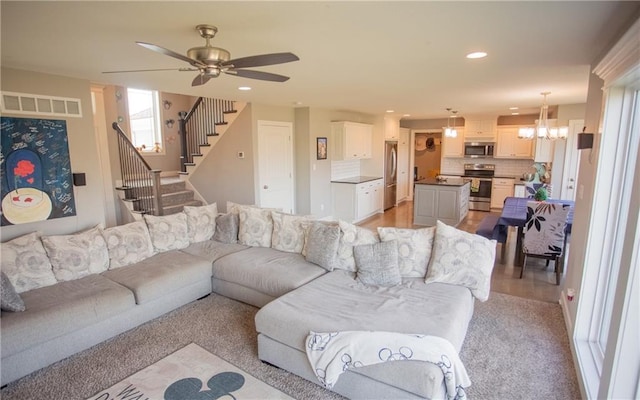 living room featuring ceiling fan with notable chandelier