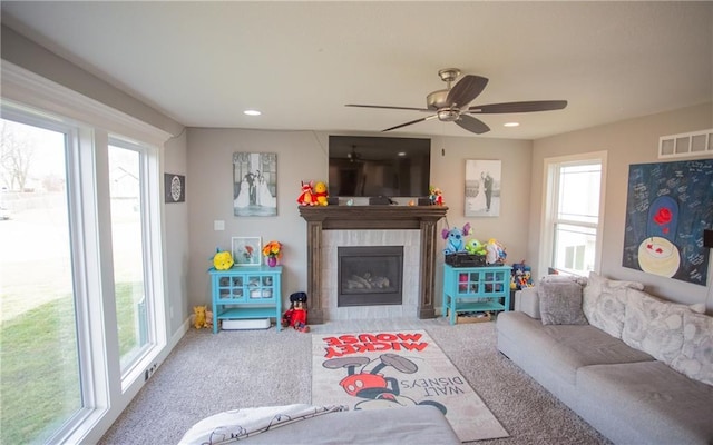 living room with a fireplace, carpet floors, ceiling fan, and plenty of natural light