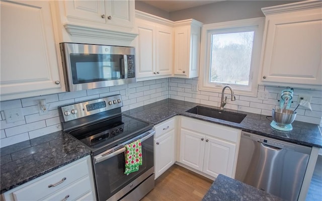 kitchen with sink, light wood-type flooring, white cabinets, and appliances with stainless steel finishes