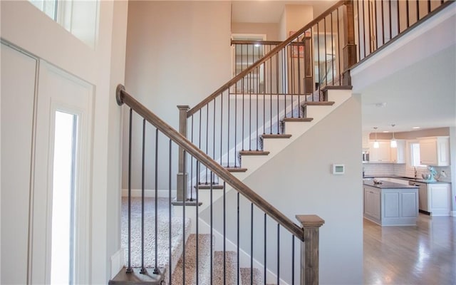 stairs featuring a towering ceiling and wood-type flooring