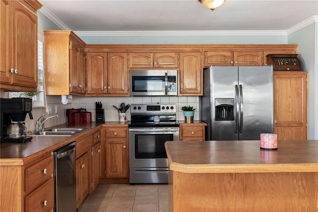 kitchen featuring dark countertops, a sink, appliances with stainless steel finishes, crown molding, and tasteful backsplash