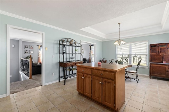 kitchen with crown molding, pendant lighting, a tray ceiling, an inviting chandelier, and brown cabinetry