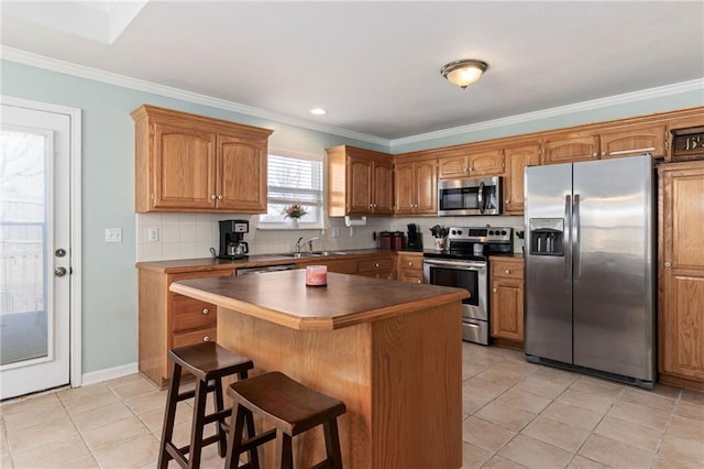 kitchen featuring ornamental molding, a kitchen breakfast bar, dark countertops, tasteful backsplash, and appliances with stainless steel finishes